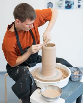 A potter works on a potter's wheel to smooth the surface of a vase