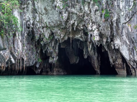 The entrance to the Puerto Princesa Underground River in Palawan features imposing karst cliffs with lush vegetation.
