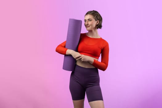 Full body length gaiety shot athletic and sporty young woman with fitness matt in exercise posture on isolated background. Healthy active and body care lifestyle.