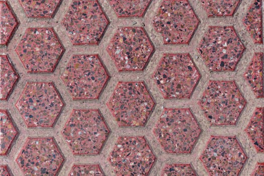 Detailed view of a pink tile with a hexagonal pattern showcasing its texture and abstract design in stone material.