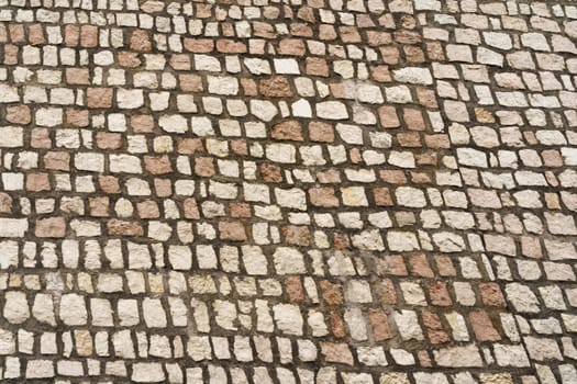 Detailed close-up view of weathered cobblestones forming a street surface with a textured and abstract pattern.