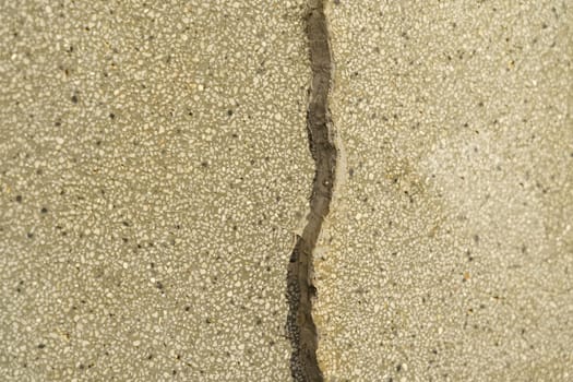 A close-up view of a cracked concrete wall, showcasing the texture and abstraction of the stone surface.