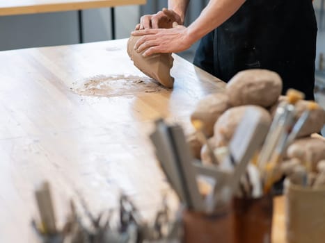 A potter kneads clay before using it in the workshop. Close-up of a man's hands