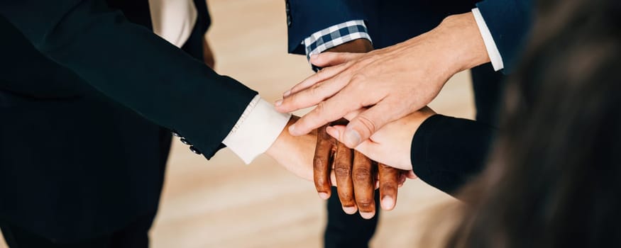 An above view of a diverse business group holding hands in a circle. This act of teamwork and togetherness in the modern office exemplifies cooperation, communication, and a sense of community.