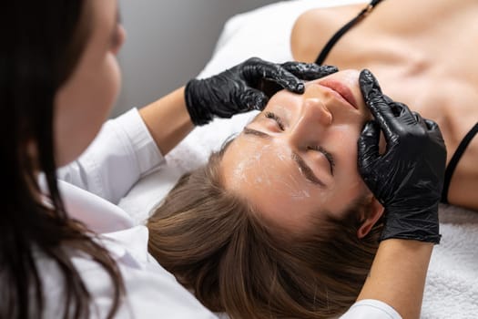 Specialist shows skillful manipulation of client facial contours. Spa worker ensures personalized treatment addressing individual needs