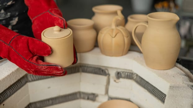 Close-up of a man's hands loading ceramics into a special kiln