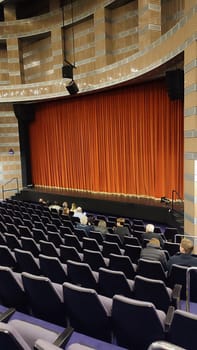 theater, auditorium, spectators sitting in chairs, scarlet curtain. High quality photo