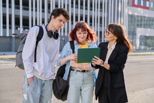 Middle aged business woman agent mentoring teacher social worker working with college university students using digital tablet outdoor