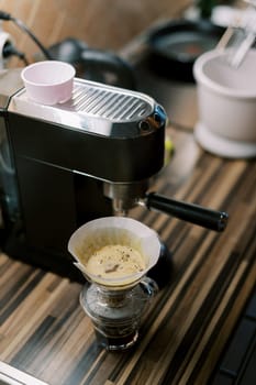 Coffee dripping through the filter of the pour over coffee maker next to the coffee machine. High quality photo