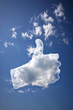A hand forming a thumbs up sign against a clear blue sky background.