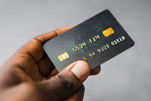 A person holding a credit card in their hand, showing the front of the card towards the camera.