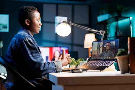 African American woman working from home, using laptop for virtual meeting with colleagues. Female freelancer engaged in online conference call, discussing and communicating remotely.