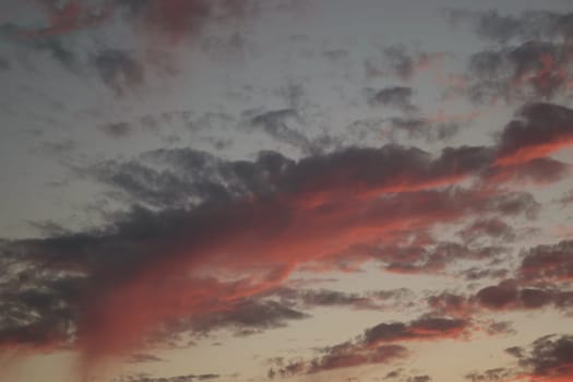 A dramatic sky at sunset with dark clouds and vibrant red and orange hues.