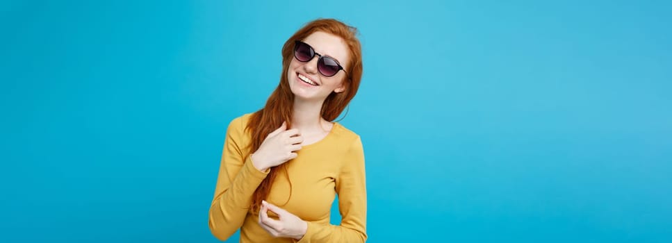 Travel concept - Close up Portrait young beautiful attractive ginger red hair girl with trendy sunglass smiling. Blue Pastel Background. Copy space