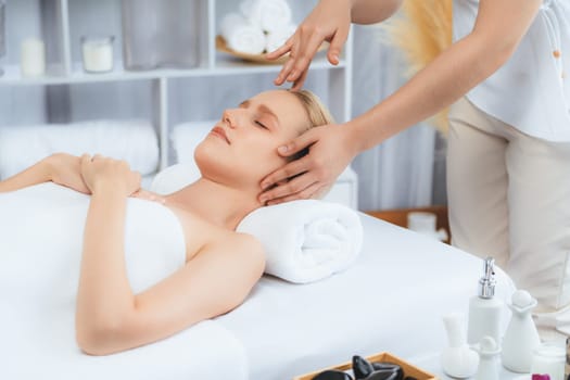 Caucasian woman enjoying relaxing anti-stress head massage and pampering facial beauty skin recreation leisure in dayspa modern light ambient at luxury resort or hotel spa salon. Quiescent