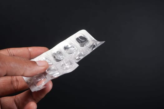 holding a empty pills of blister pack against black background ,