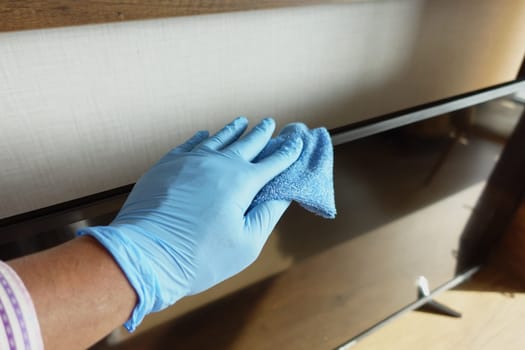 a man wipes dust from a plasma TV.