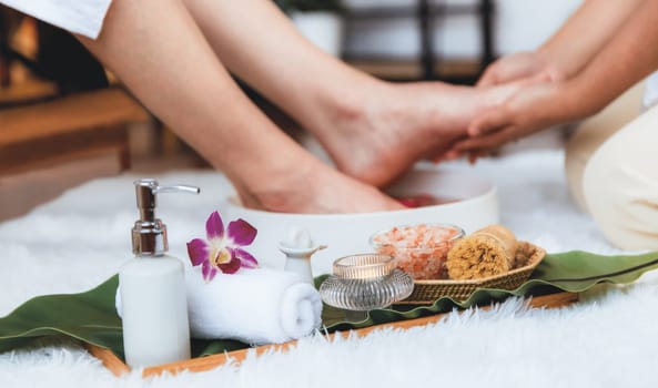 Man indulges in blissful foot massage at luxurious spa salon while masseur give reflexology therapy in gentle day light ambiance resort or hotel foot spa. Quiescent