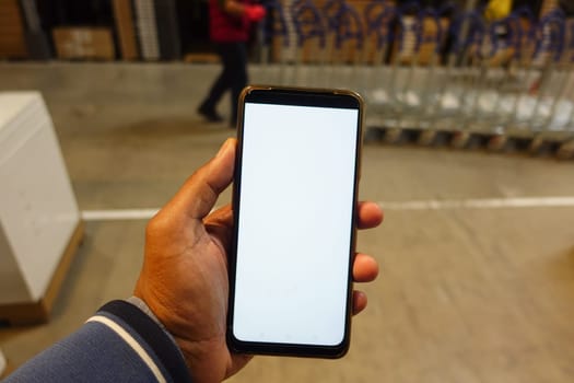 business owner holding phone mock up in warehouse