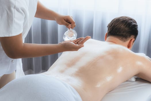 Masseur hands pouring aroma oil on man back. Masseuse prepare oil massage procedure for customer at spa salon in luxury resort. Aroma oil body massage therapy concept. Quiescent