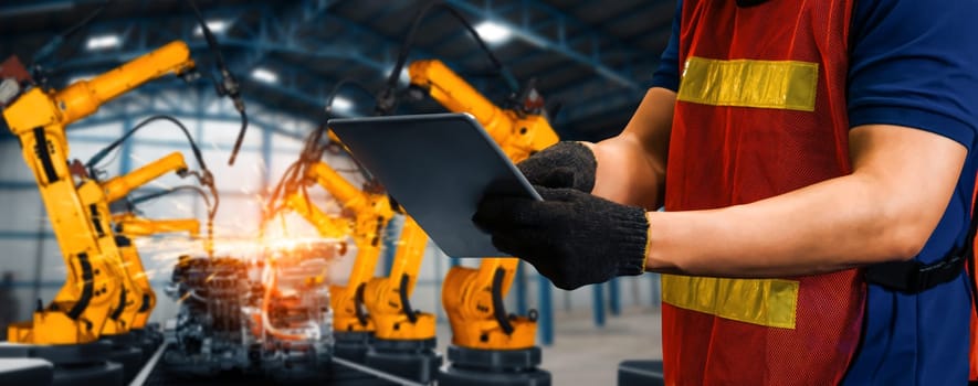 MLB Engineer use advanced robotic software to control industry robot arm in factory. Automation manufacturing process controlled by specialist using IOT software connected to internet network.