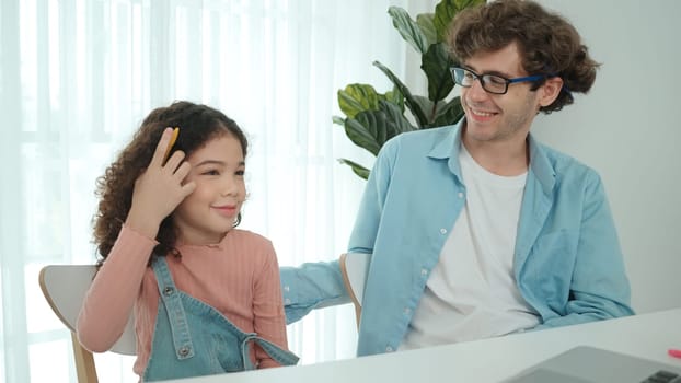 Caucasian father put on pencil on ear while daughter looking at dad and put pencil on ear. Smart dad writing engineering code and generated AI by using laptop. Family spend time together. Pedagogy.