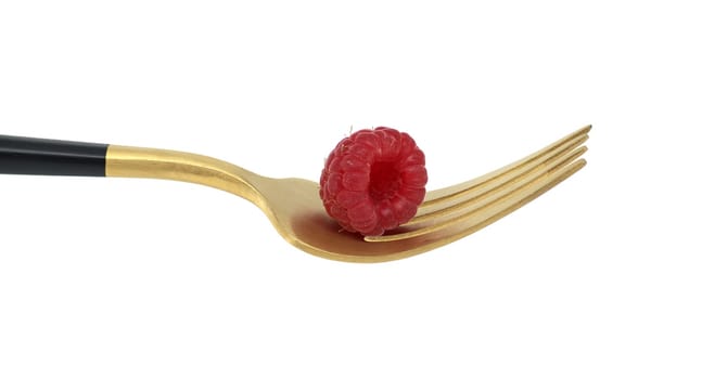 Red raspberry arranged on gold fork with a black handle, set against a white background, symbolizing a concept of healthy diet and organic food