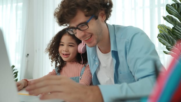 Caucasian dad put headphones on daughter while girl learning code. Father take care schoolgirl while teaching writing engineering prompt and generate Ai by using laptop. Online learning. Pedagogy.