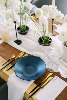 Black plate stands on a white napkin on a festive table near the menu. High quality photo