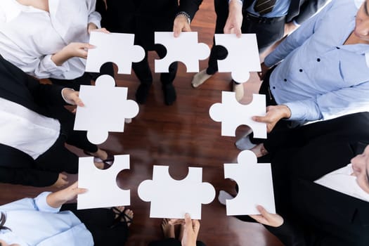 Top view multiethnic business people holding jigsaw pieces and merge them together as effective solution solving teamwork, shared vision and common goal combining diverse talent. Meticulous