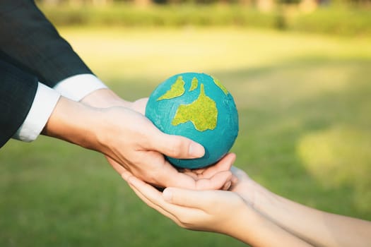 Businessman hand giving Earth globe to little boy as Earth day concept as corporate social responsible to contribute greener environmental protection for sustainable future generation. Gyre