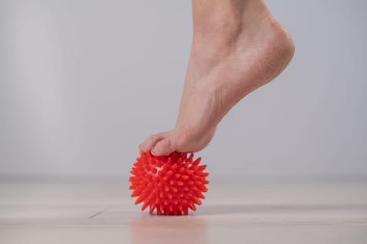 Close-up of a woman's foot on a massage ball with spikes