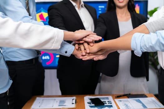 Multiracial business people make synergy hand stack together in meeting room as cooperation or team building for corporate employee in workplace. Meticulous