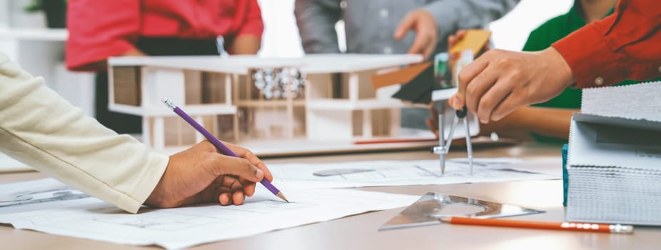 Professional architect team select sustainable house materials while skilled engineer using divider measure blueprint with house model and color palette placed on meeting table. Closeup. Variegated.