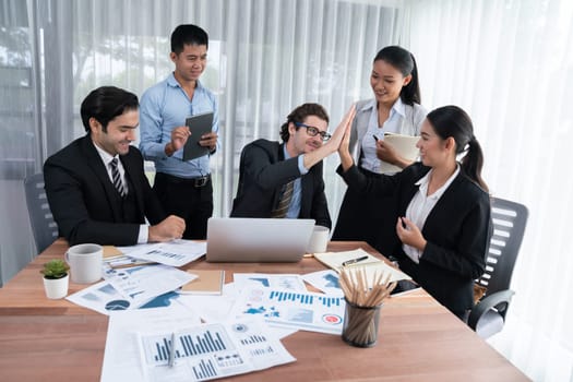 Group of happy businesspeople in high five gesture and successful efficient teamwork. Diverse race office worker celebrate after made progress on marketing planning in corporate office. Habiliment