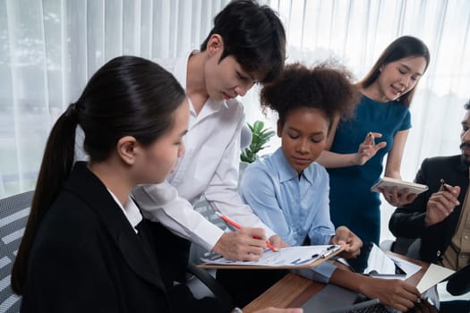 Multiracial analyst team use BI dashboard data to analyze financial report on meeting table. Group of diverse business people utilize data analysis by FIntech for business marketing decision. Concord