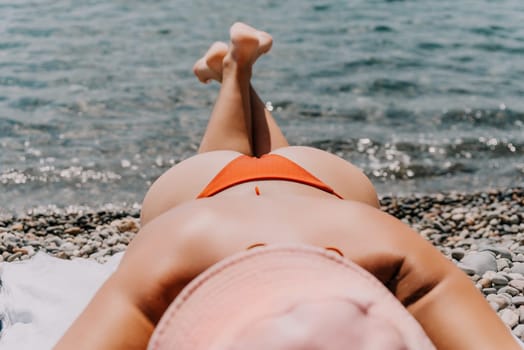 Happy smiling young woman sunbathing or tanning on a seaside beach during summer vacation. Slow motion of happy tourist in red swimsuit enjoying sun tan lying on beach chair lounge at luxury resort.