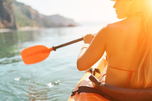 woman bikini paddles kayak on a lake. The sun is shining brightly, creating a warm and inviting atmosphere