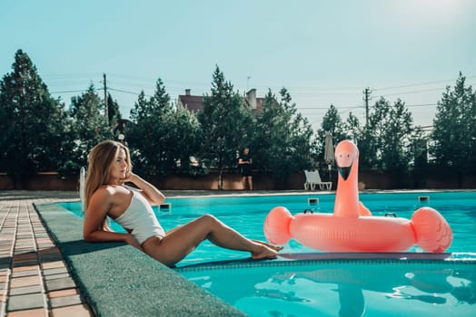 A woman is laying in a pool with a pink flamingo float. The scene is relaxing and fun, with the woman enjoying her time in the water
