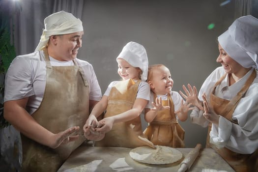 Cute oriental family with mother, father, daughter, son cooking in kitchen on Ramadan, Kurban-Bairam. Funny family at photo shoot. Easter