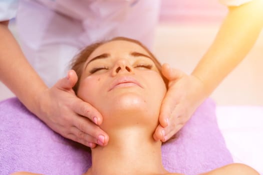 Relaxing massage. European woman getting facial massage in spa salon, side view.