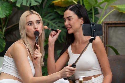 Two beautiful content creator making natural beauty and cosmetic tutorial on green plant garden video. Beauty blogger showing how to beauty care to social medial audience using selfie stick . Blithe