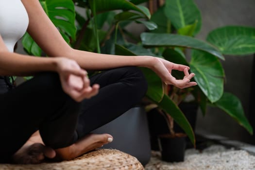 Young woman doing morning yoga and meditation in natural garden with plant leaf, enjoying the solitude and practicing meditative poses. Mindfulness activity and healthy mind lifestyle. Blithe