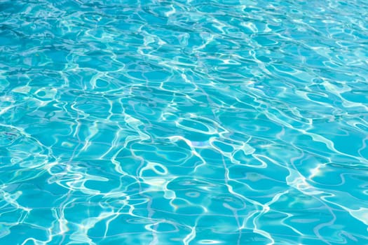 Blue swimming pool water surface and ripple wave background. Summer abstract reflection caustics in swimming pool.