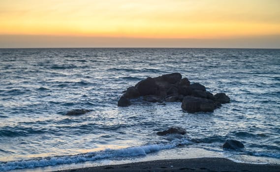 stones in the Mediterranean sea near the beach at sunset