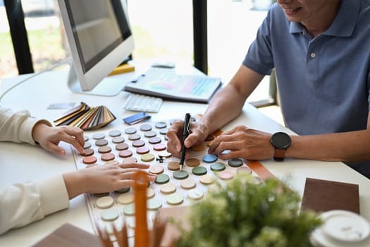 Cropped shot client choosing colors in swatches palette for apartment renovation.