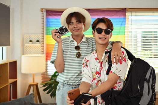 Gay couple tourists wearing summer clothes getting ready for vacation trip. Homosexual relationship concept.