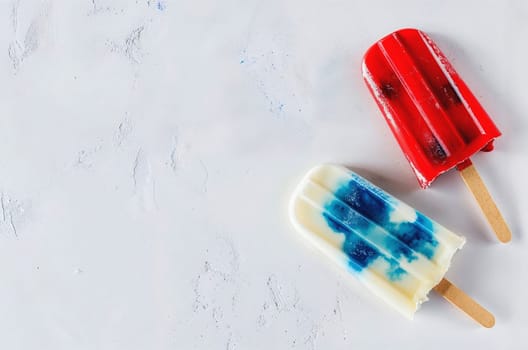 Red, blue and white popsicles on blue, top view, summer concept, space for text