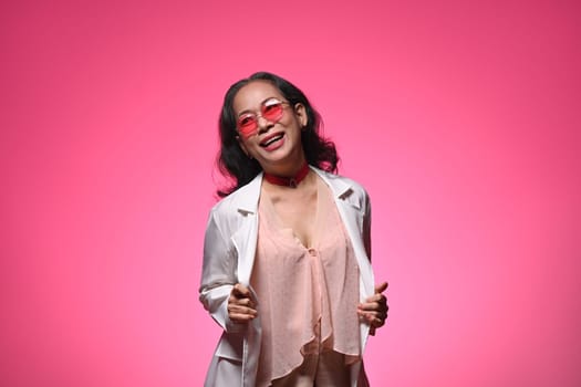 Portrait of a cheerful middle aged woman with fashionable outfit posing over pink background.