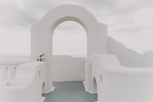 A white bouquet of flowers sits on a white wall. The flowers are white and green, and they are arranged in a vase. The vase is placed on a ledge, and the bouquet is the main focus of the image